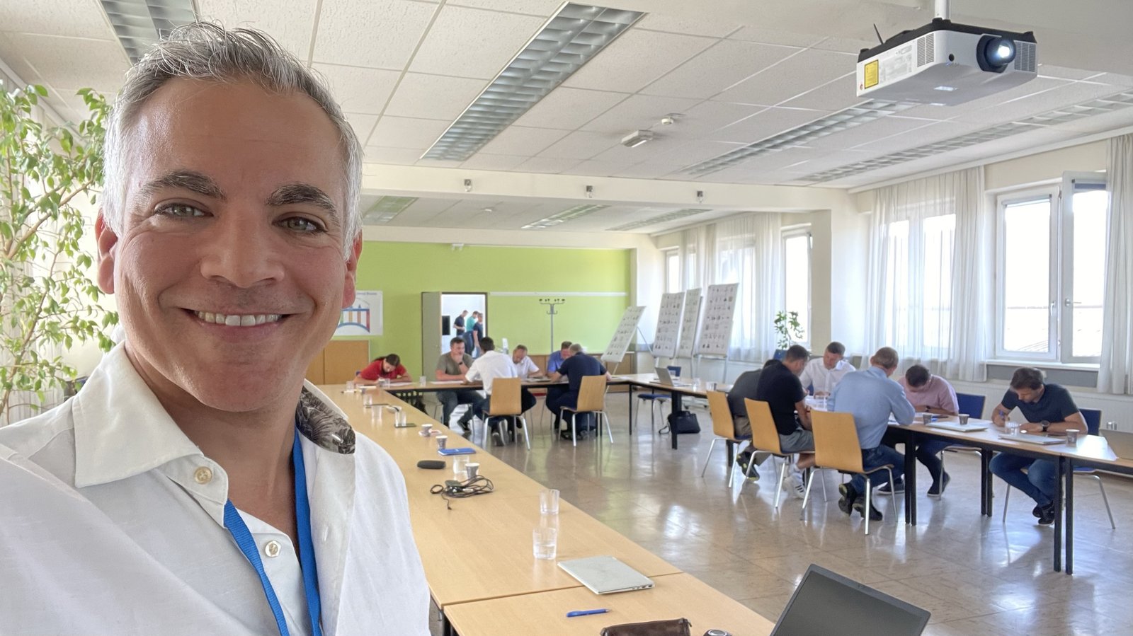 Anwar von Colberg in einem Workshop, Teilnehmer arbeiten an Tischen im Hintergrund